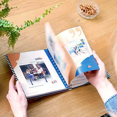 Een vriendenboek met fotopagina's als cadeau doorbladeren aan tafel